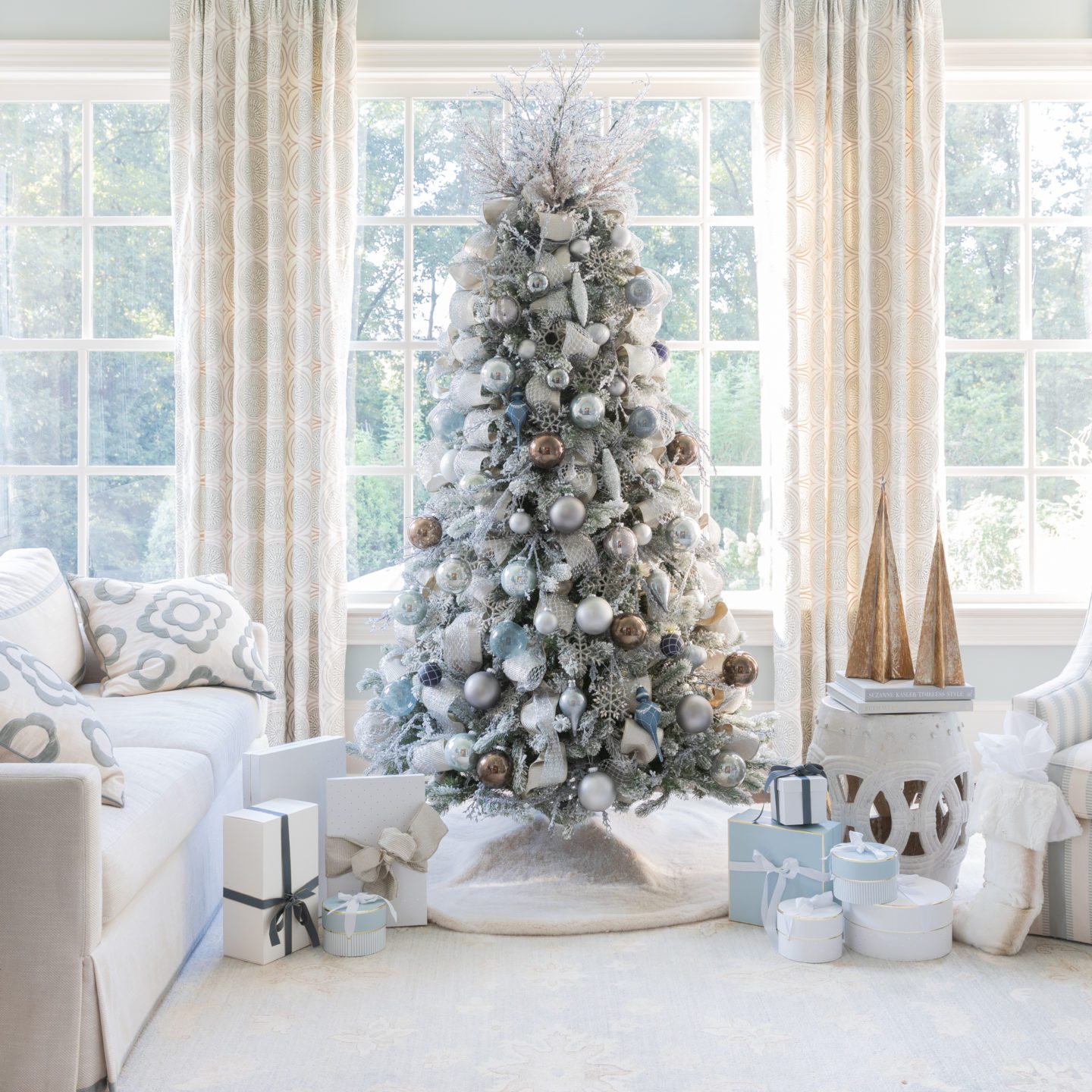 Flocked Christmas tree covered in blue, silver, brown, and gray ornaments and ribbon.