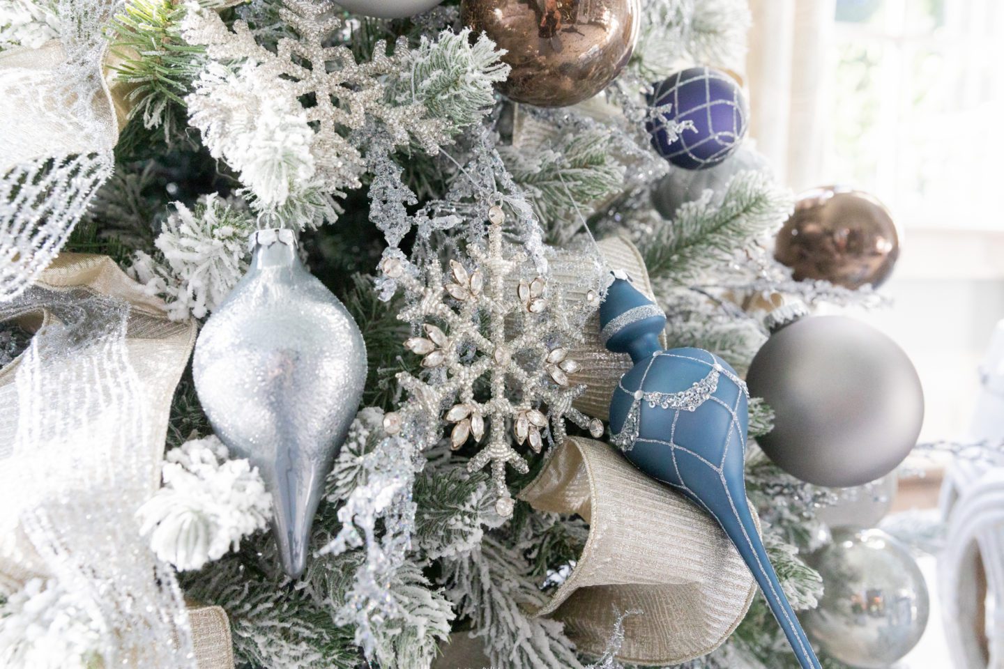 elegant blue, silver and brown ornaments and snowflakes glitter ornamnts on a flocked Christmas tree