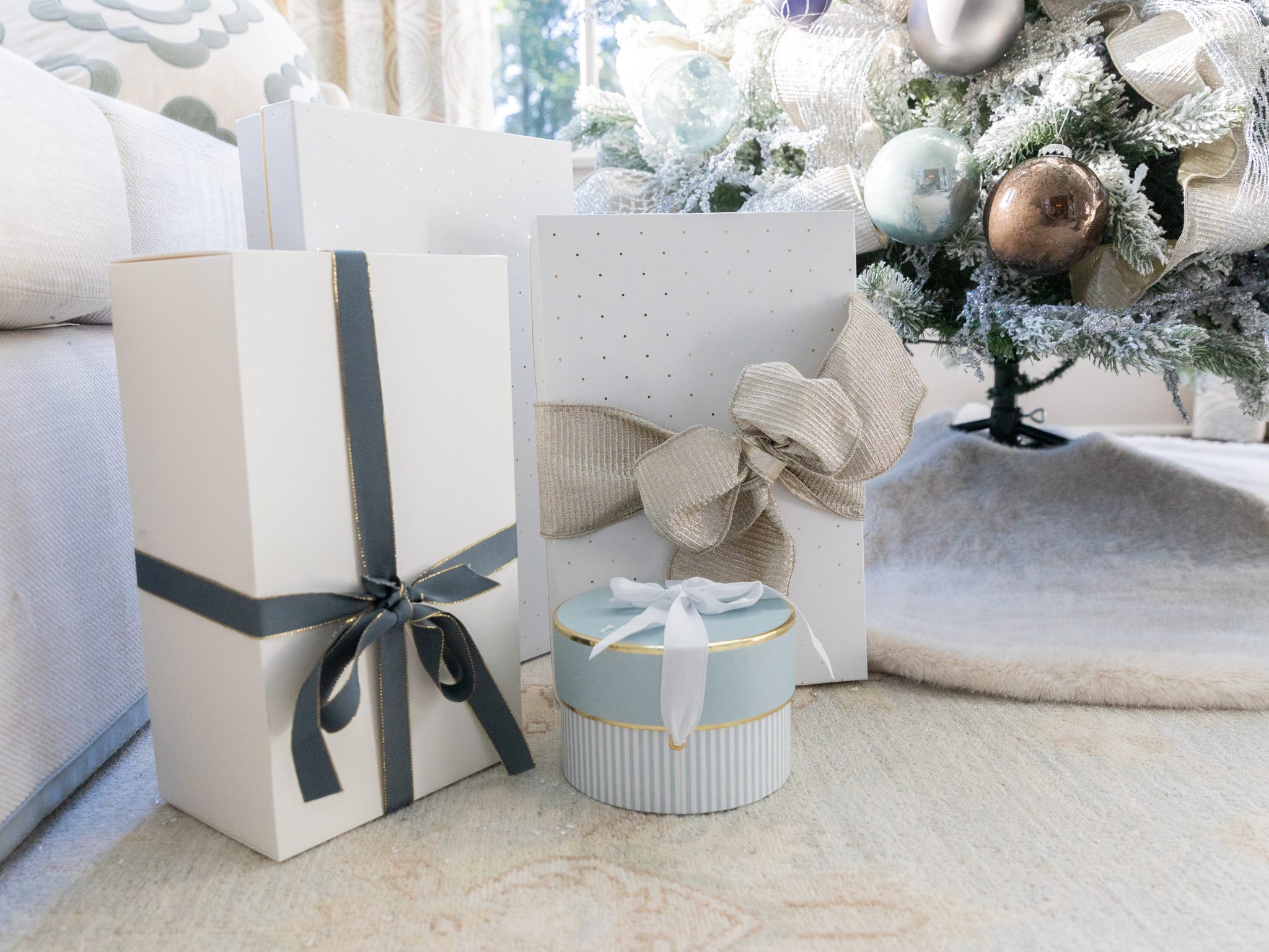 White accent gift boxes under a flocked Christmas tree