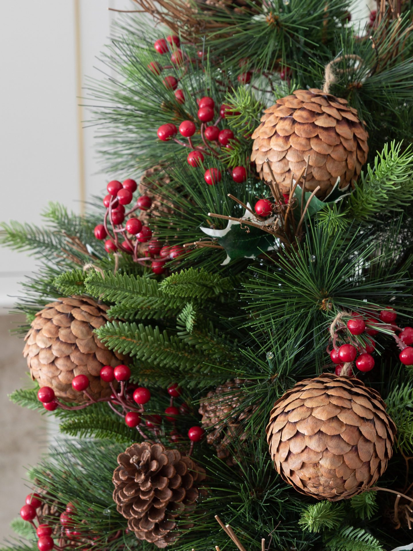 Pinecone ornaments and holly picks on a green Christmas tree
