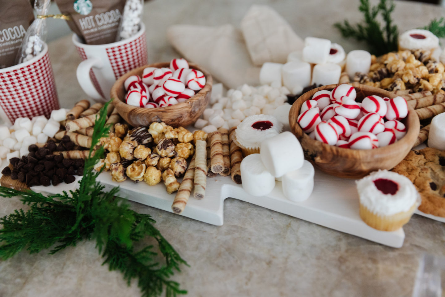 A Christmas tree charcuterie board covered in white and red desserts